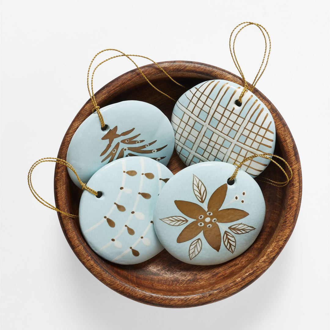 Close-up of hand-painted blue paper mache Christmas ornament with red green and gold holiday design