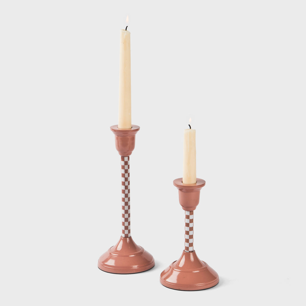 Pair of sculpted aluminum candlestick holders in dusty pink with a subtle checkered pattern.