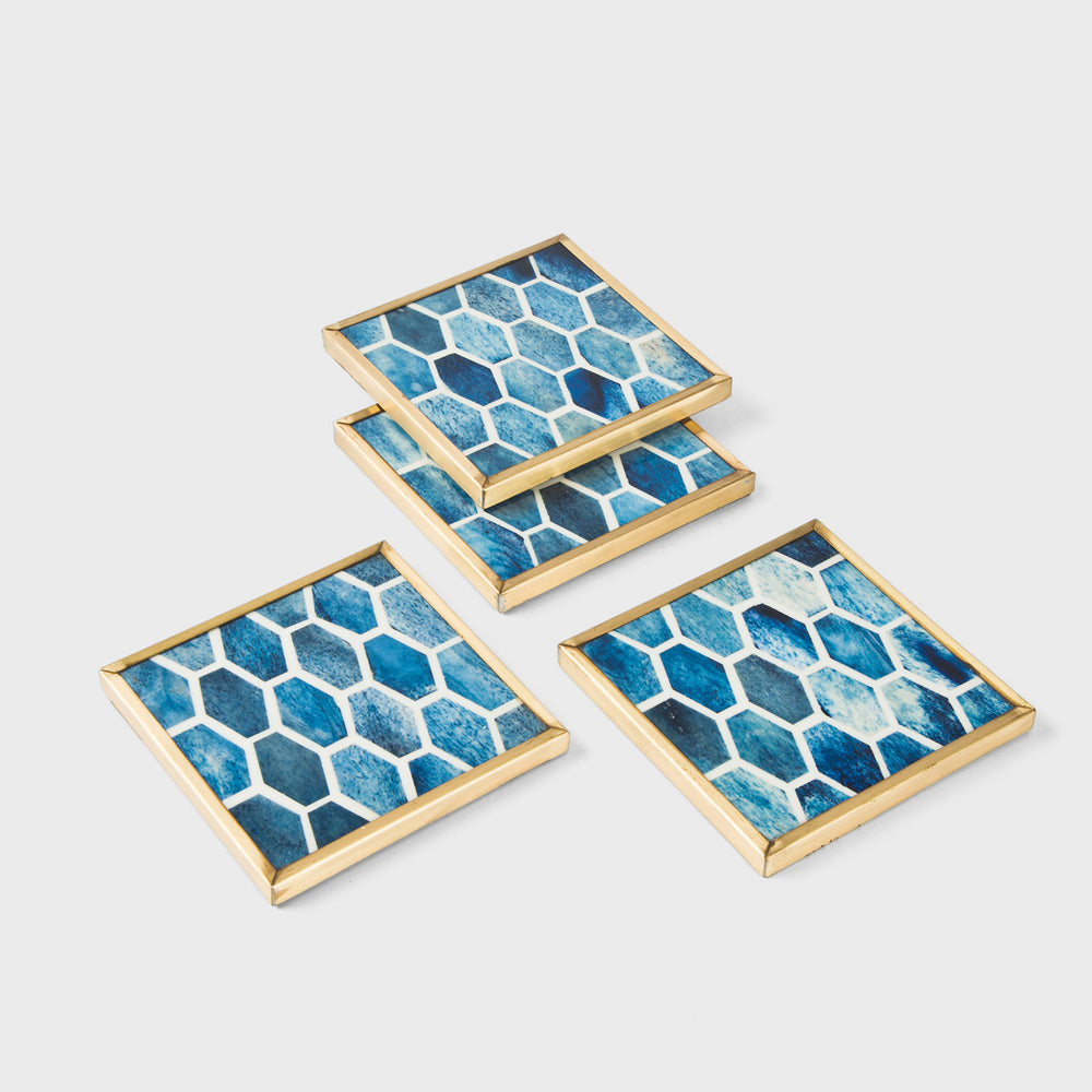 Set of 4 square deep blue resin coasters with a geometric honeycomb pattern and polished brass edges.
