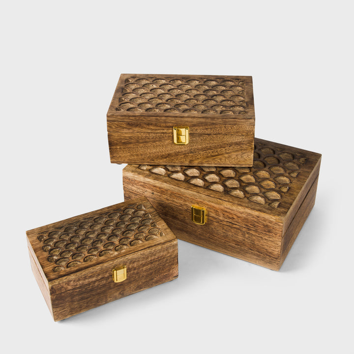 Three rectangular wooden storage boxes with interlocking carved lid designs and small gold-tone latches, arranged on a light gray studio background.