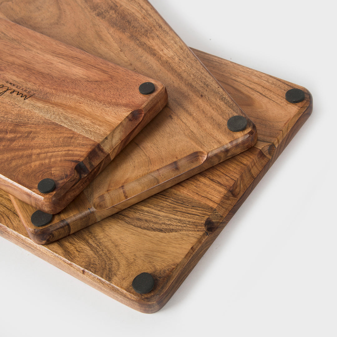 acacia wood cutting board set styled with bread cheese and fruit on kitchen counter
