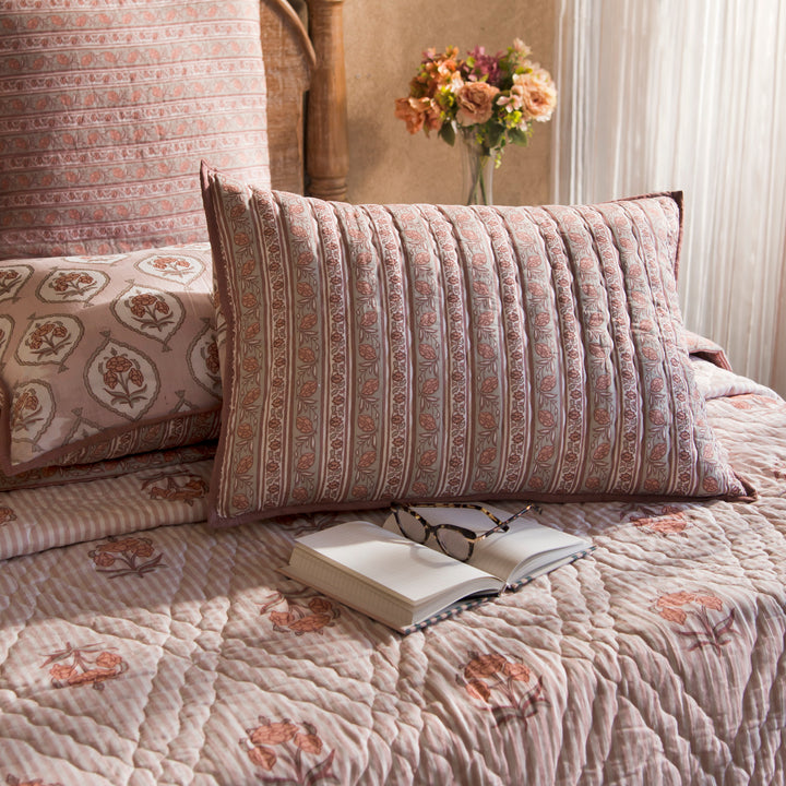 Kunj standard blush pink shams styled on a bed layered with quilt and cushions