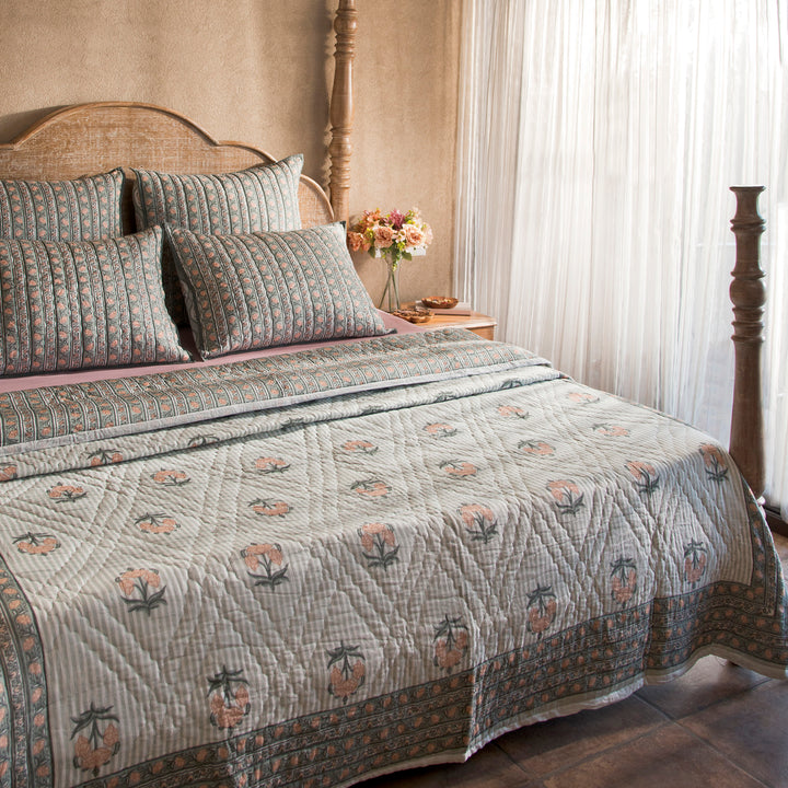 Green Block printed quilt styled on a bed with coordinated cushions and décor