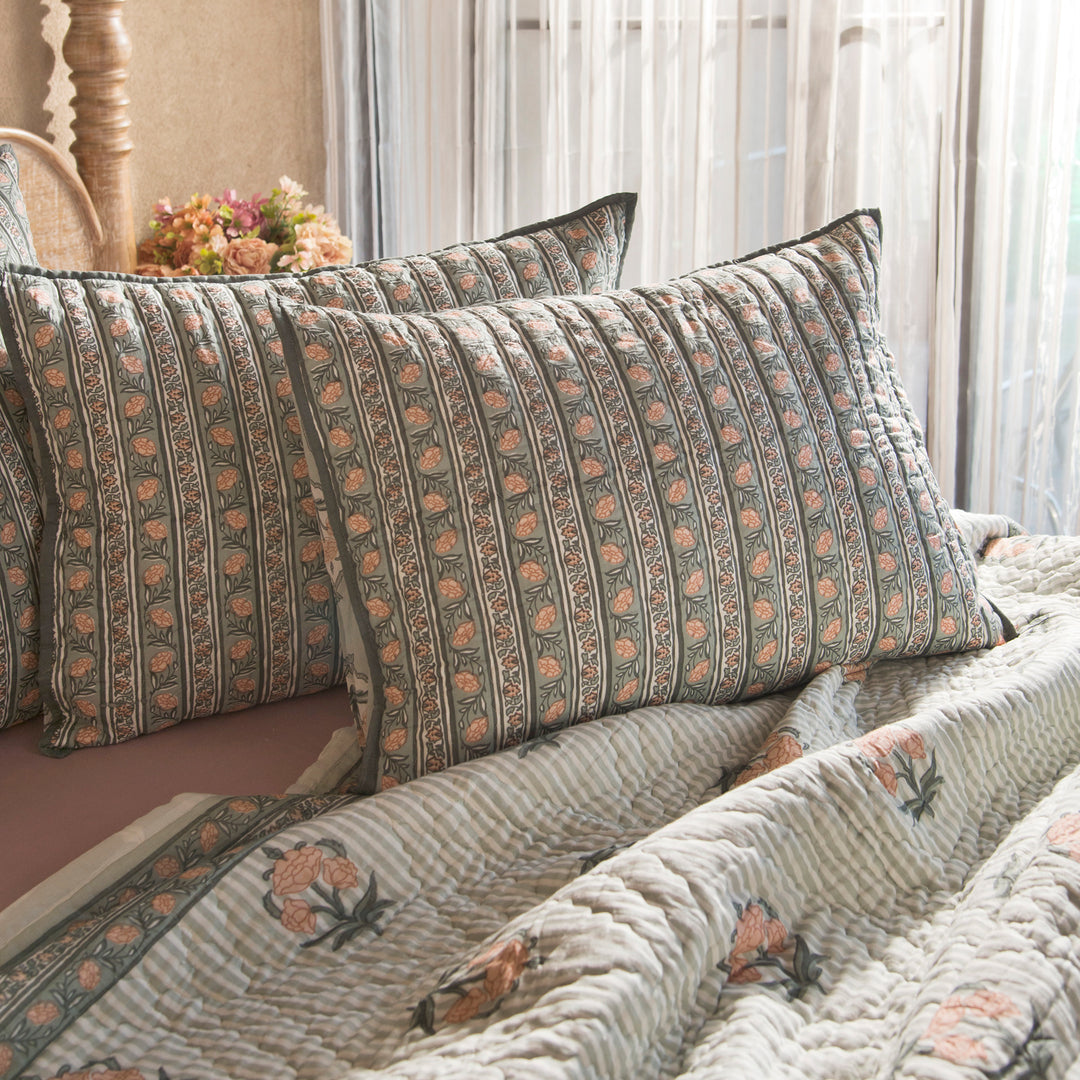 Kunj standard green shams styled on a bed layered with quilt and cushions