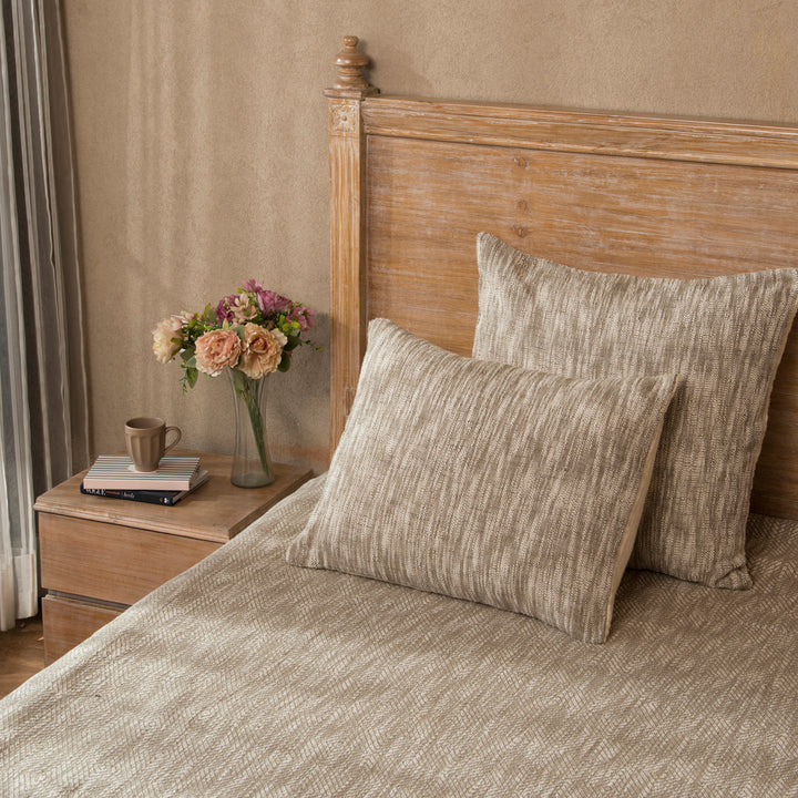 Earthy shams styled on a bed layered with quilt and cushions