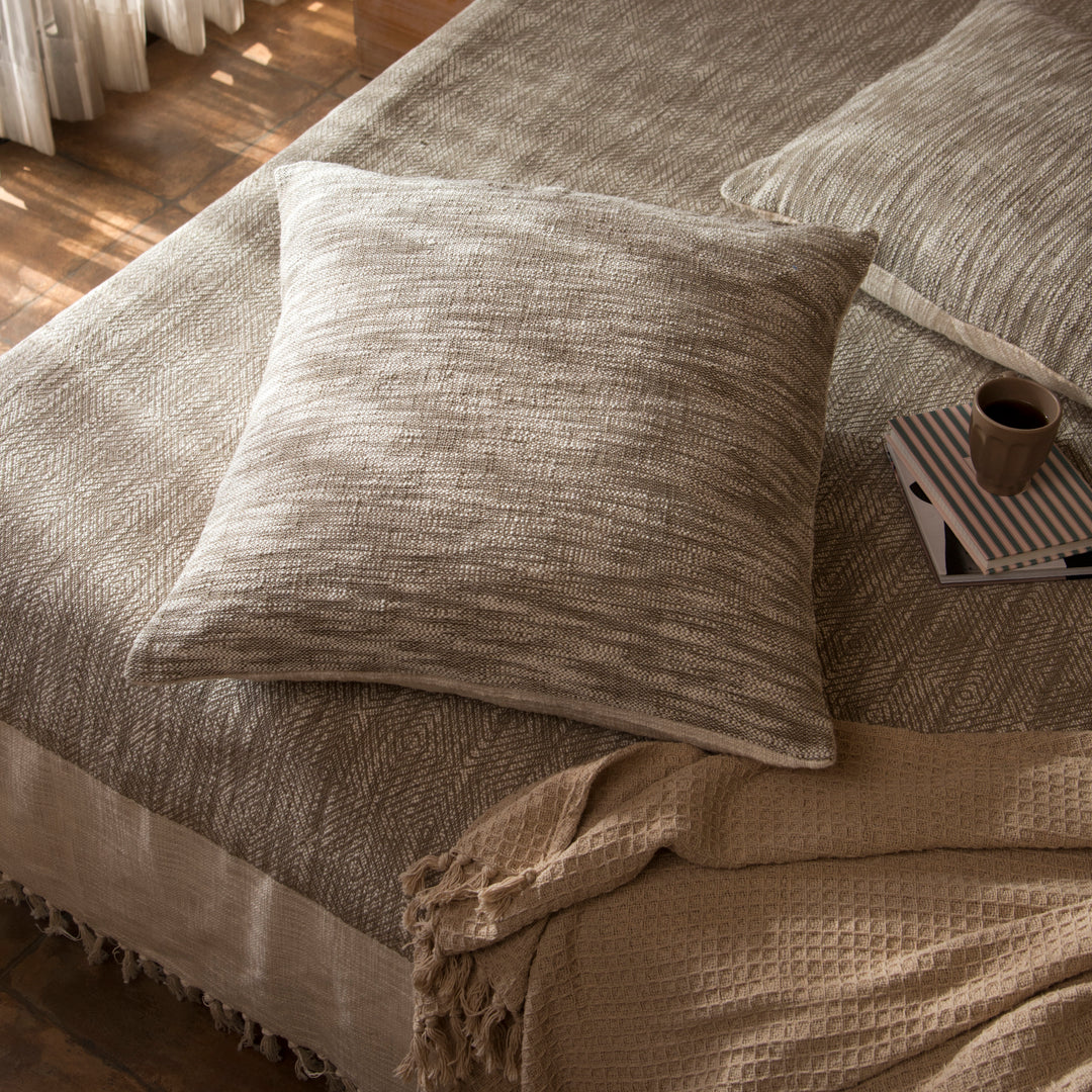 Earthy euro shams styled on a bed layered with quilt and cushions