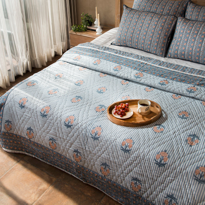 Blue Block printed quilt styled on a bed with coordinated cushions and décor