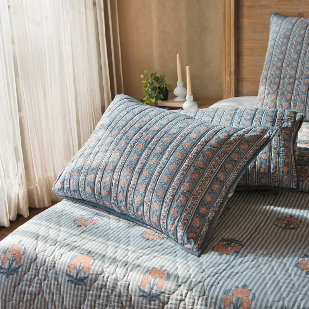 Kunj standard blue shams styled on a bed layered with quilt and cushions