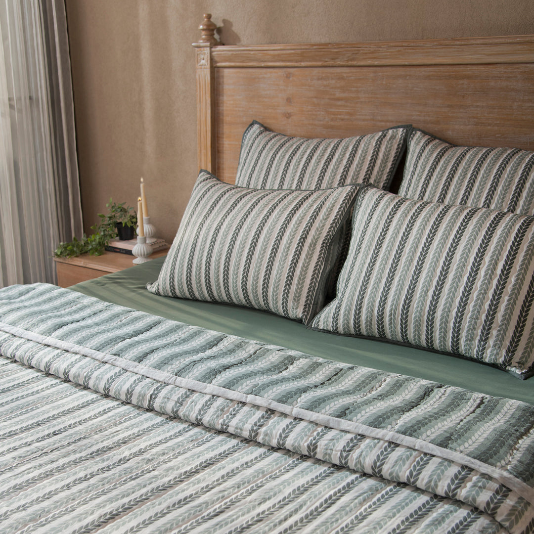 Green leafy stripes reversible cotton quilt in single size displayed on bed
