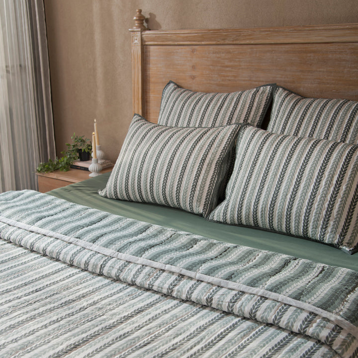 Green leafy stripes reversible cotton quilt in single size displayed on bed
