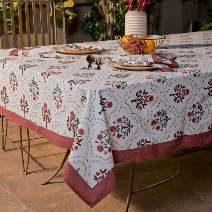 Rust and maroon floral printed cotton tablecloth spread on dining table
