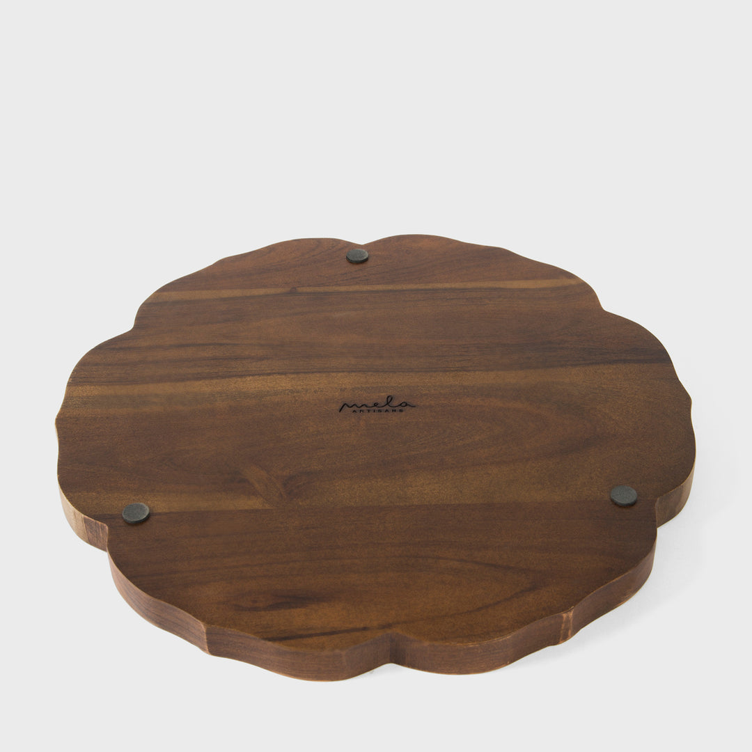 Close-up of scalloped border craftsmanship and hand painted cream and terracotta bamboo leaves on dark wood grain 