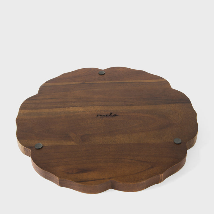 Close-up of scalloped border craftsmanship and hand painted cream and terracotta bamboo leaves on dark wood grain 