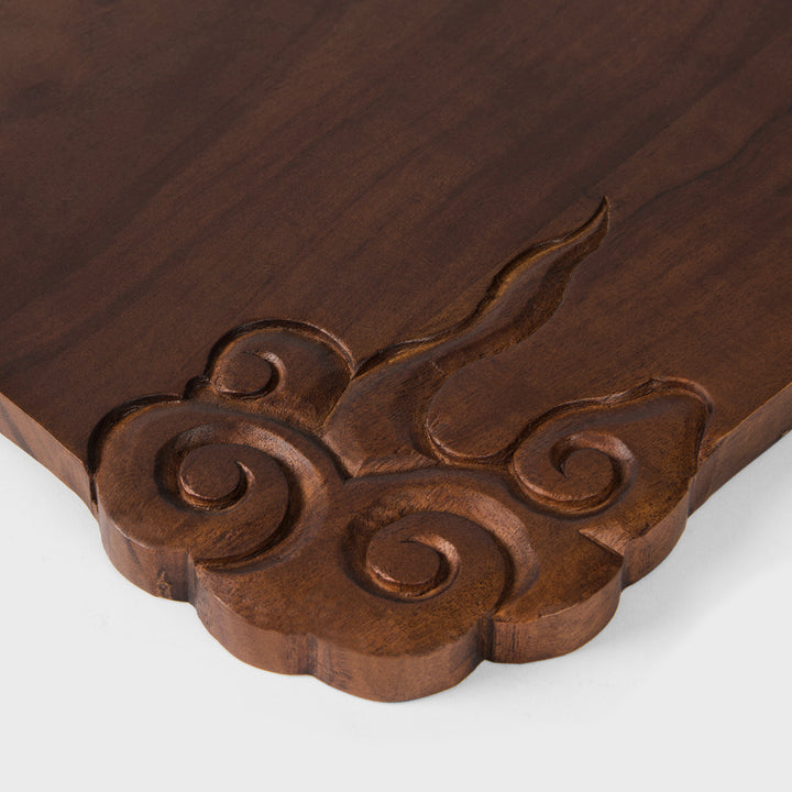 Close-up of corner relief carving showing hand carved cloud details on dark wood grain