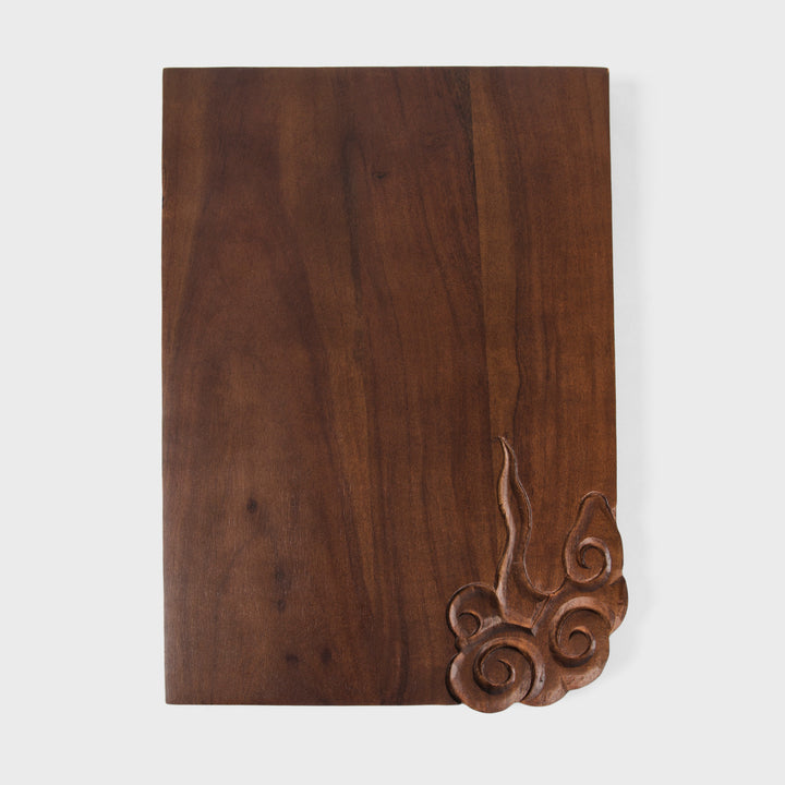 Close-up of corner relief carving showing hand carved cloud details on dark wood grain