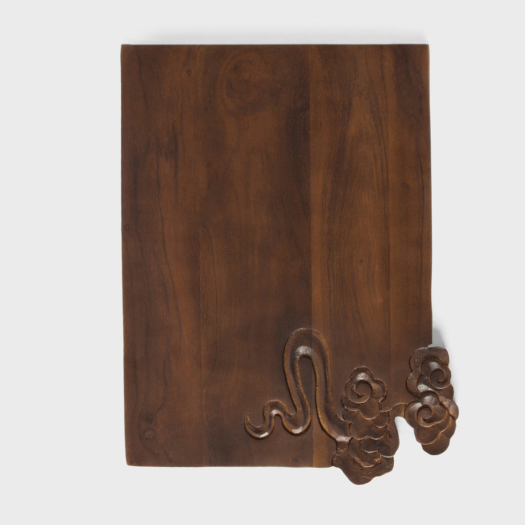 Close-up view of split-edge hand-carved cloud and wave details on dark acacia wood grain