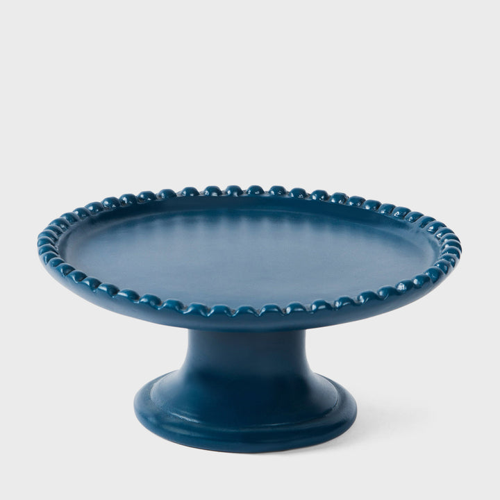 Handcrafted matte indigo terracotta cake stand with a raised beaded rim and pedestal base by Mela Artisans.
