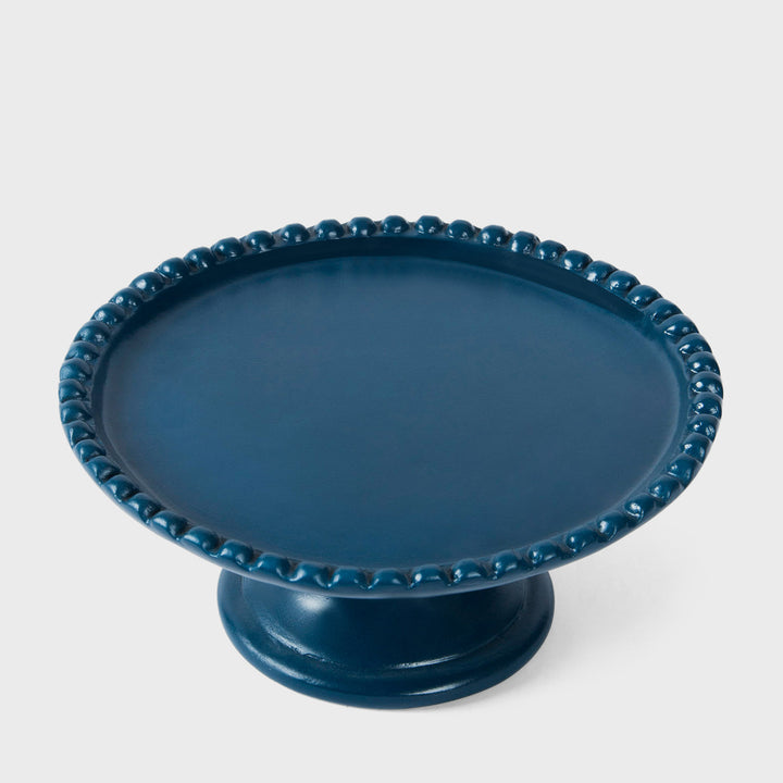 Handcrafted matte indigo terracotta cake stand with a raised beaded rim and pedestal base by Mela Artisans.
