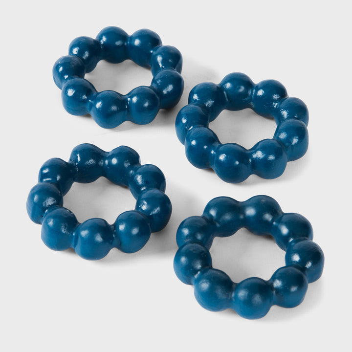 Set of four handcrafted matte indigo terracotta napkin rings with sculptural bubble-beaded detailing by Mela Artisans.