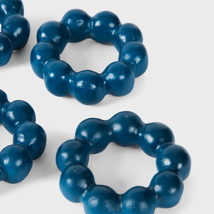 Close-up of the handcrafted terracotta napkin ring showcasing its matte indigo glaze and spherical bubble-beaded design.
