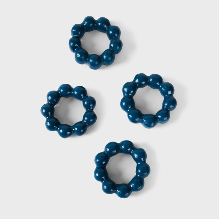 Set of four handcrafted matte indigo terracotta napkin rings with sculptural bubble-beaded detailing by Mela Artisans.