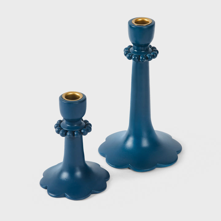 Close-up of the handcrafted terracotta candle holders showcasing the matte indigo glaze, raised bead accents, and sculptural scalloped base.