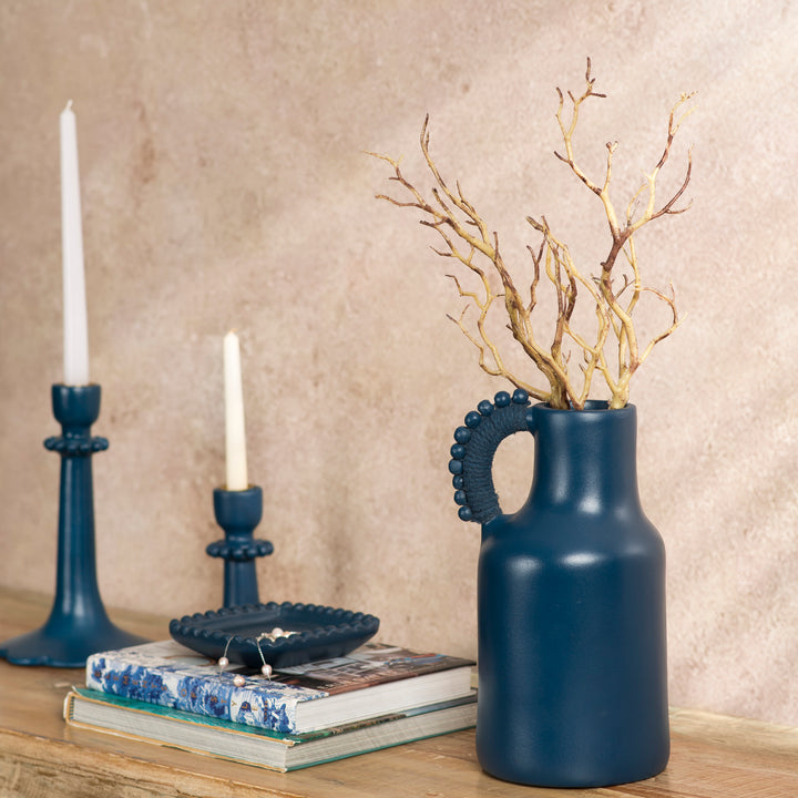 Handcrafted terracotta pitcher styled as a vase with fresh flowers on an artisan-inspired dining table.