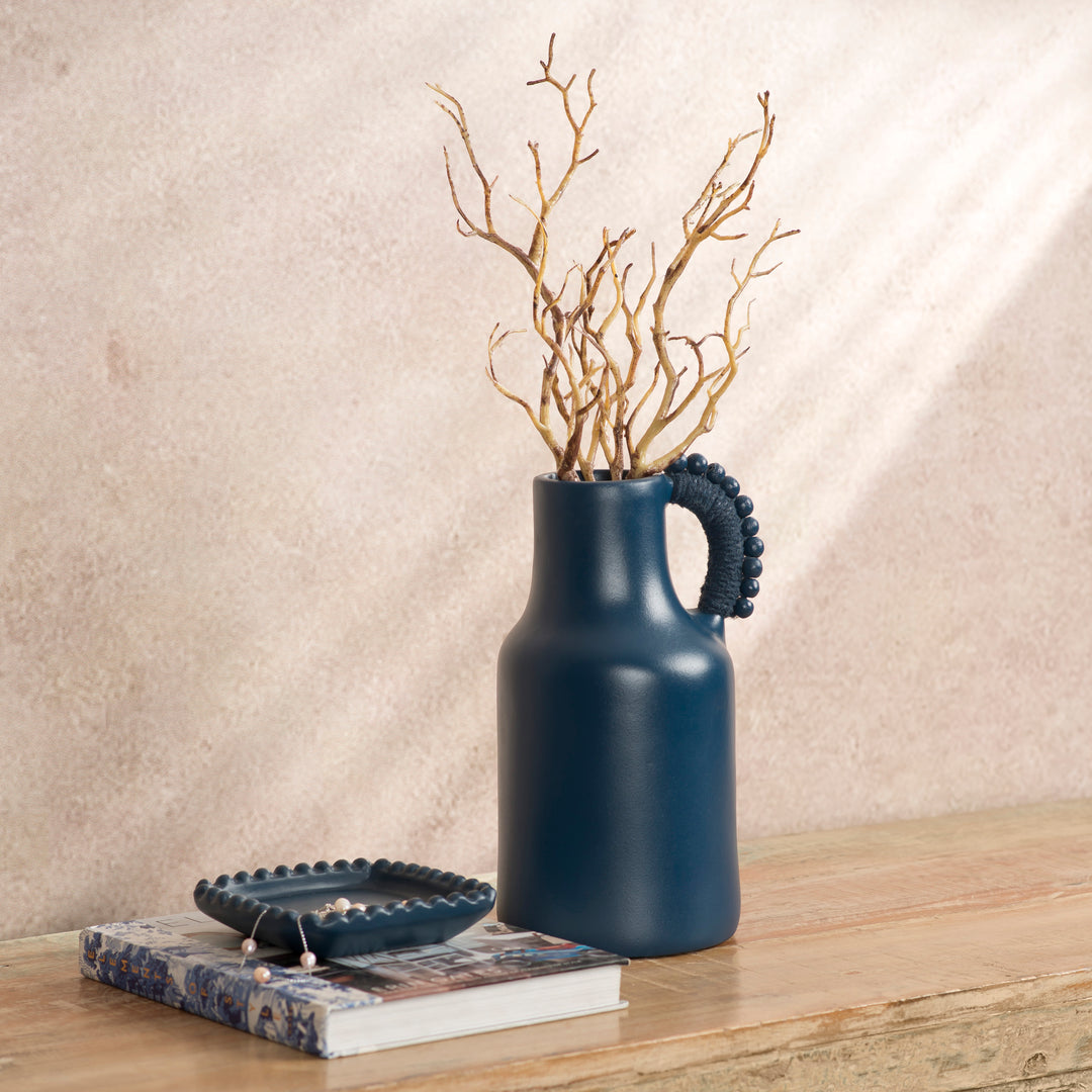 Handcrafted terracotta pitcher styled as a vase with fresh flowers on an artisan-inspired dining table.