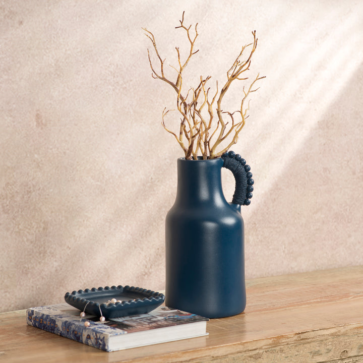 Handcrafted terracotta pitcher styled as a vase with fresh flowers on an artisan-inspired dining table.