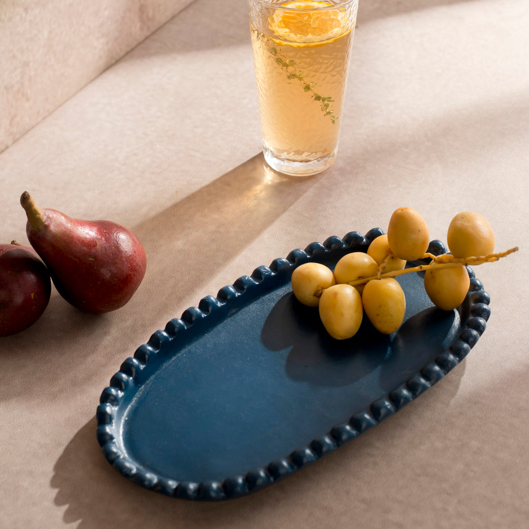 Handcrafted terracotta serving platter styled with cheeses, fresh fruit, and appetizers on an artisan-inspired dining table.
