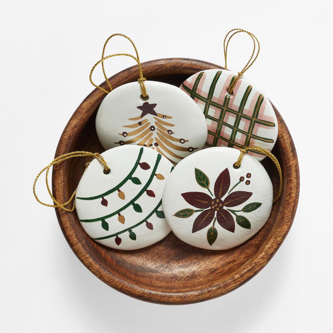 Close-up of hand-painted white paper mache Christmas ornament with red green and gold holiday design