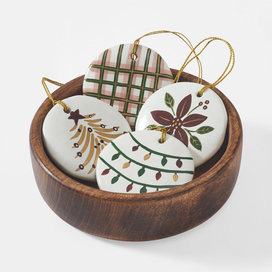 Close-up of hand-painted white paper mache Christmas ornament with red green and gold holiday design