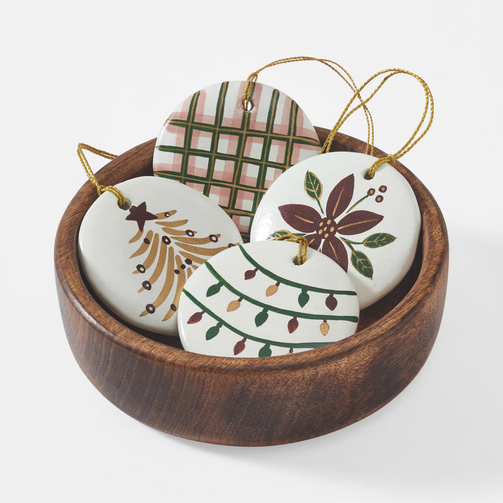 Close-up of hand-painted white paper mache Christmas ornament with red green and gold holiday design