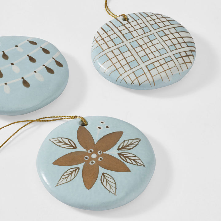 Close-up of hand-painted blue paper mache Christmas ornament with red green and gold holiday design