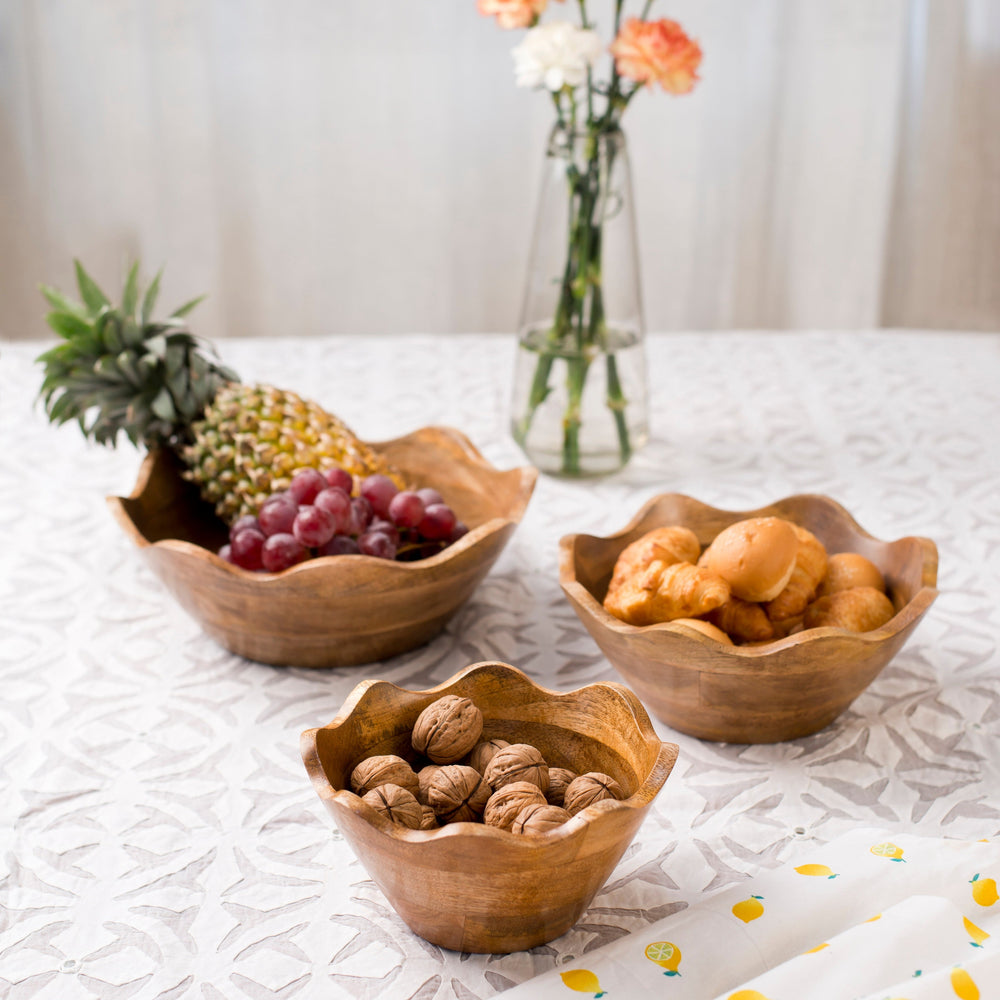 A scalloped mango wood bowl filled with walnuts and styled with natural linen and dried botanicals for a rustic, farmhouse aesthetic.