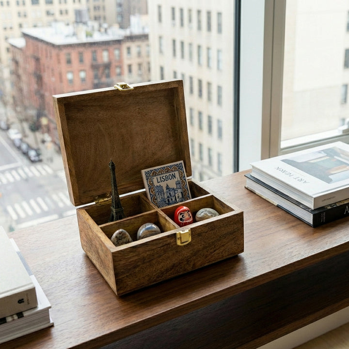 A small rectangular wooden box with an open lid with 4 compartments styled with decorative items.