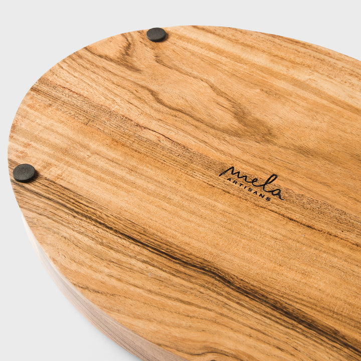 Close-up of natural acacia wood grain and carved handle detail on oval tray