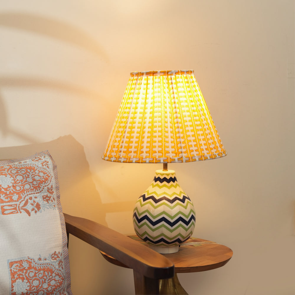 Lit Chevron table lamp casting a warm glow in a living room, highlighting the intricate bone and resin textures.