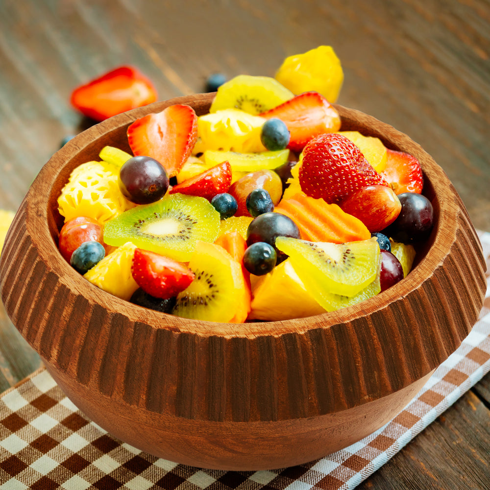 large wooden serving bowl styled with salad on dining table