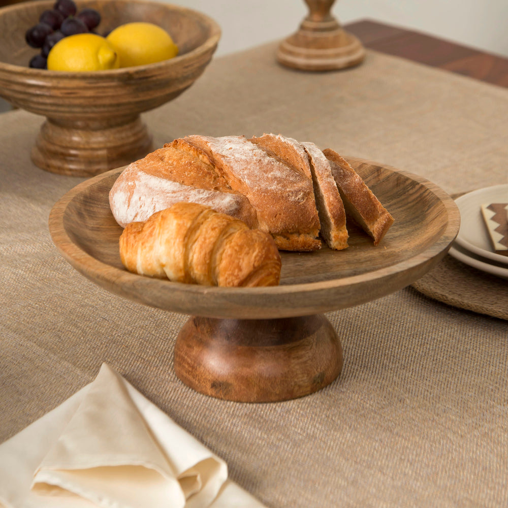 Wooden pedestal bowl styled as centerpiece with fruits on dining table