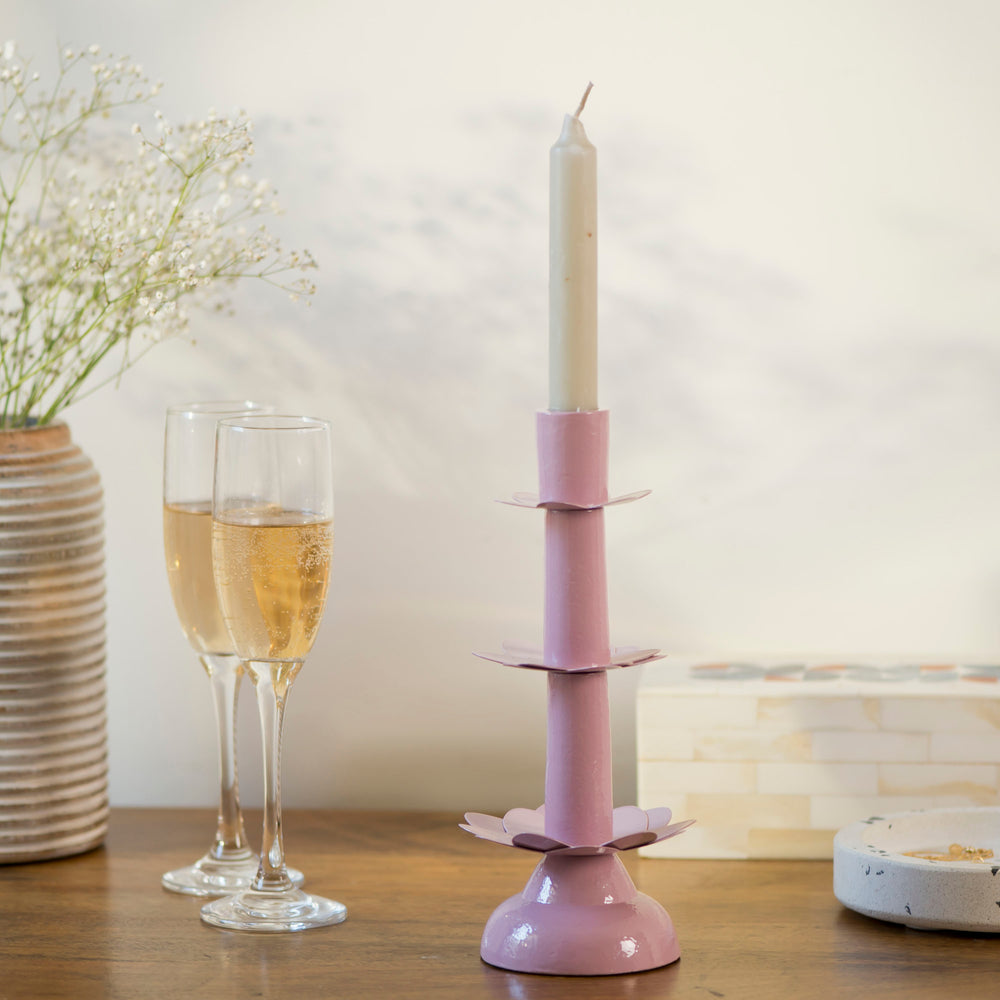 Handcrafted pink lotus candleholder styled on a wooden table alongside two champagne flutes and delicate white flowers.