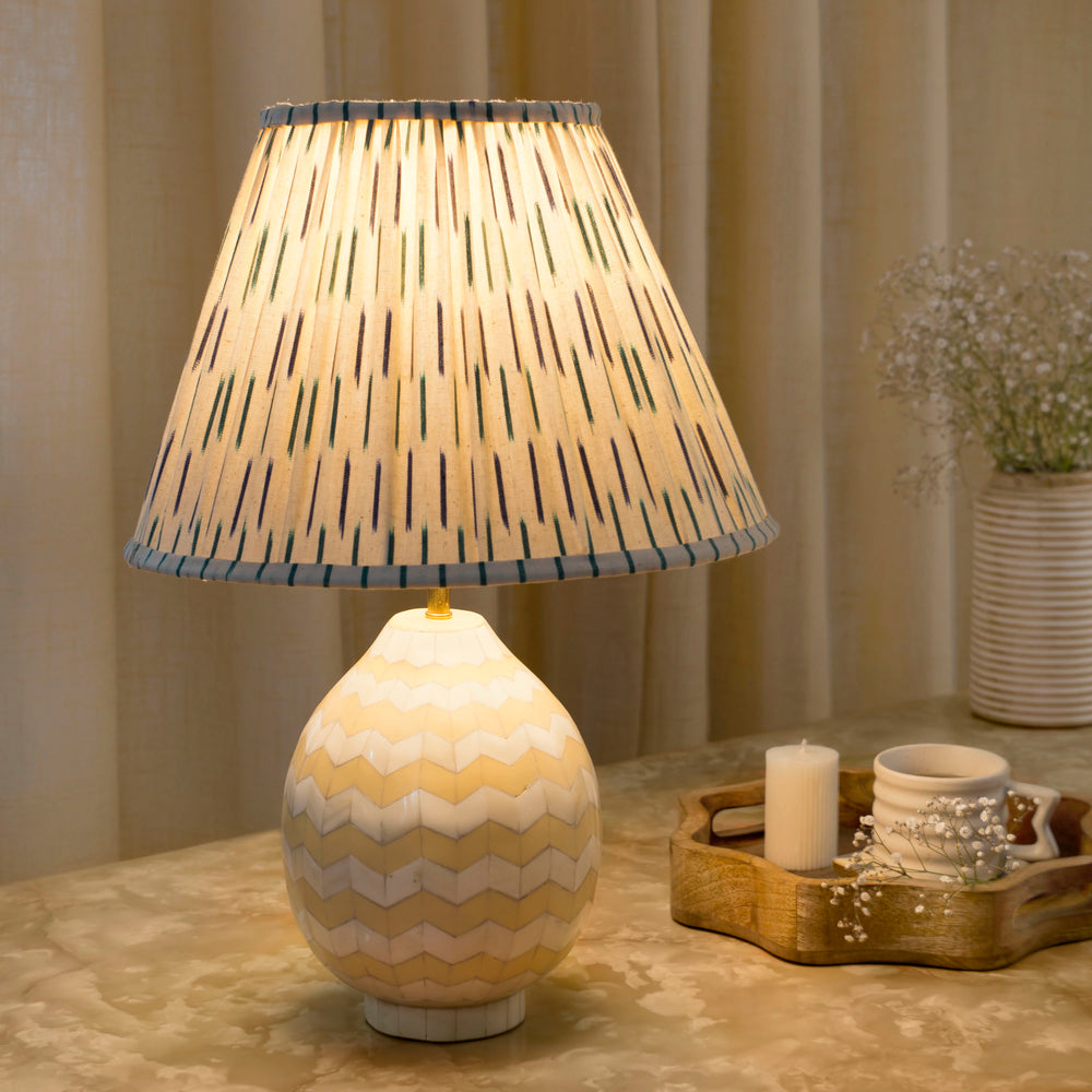 A cozy living room scene featuring the Herringbone Inlay lamp lit on a side table, highlighting the natural texture and warm glow of the ivory tones.