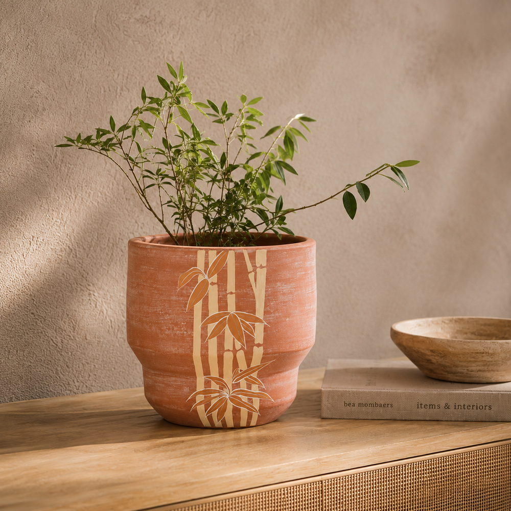 Japandi style terracotta plant pot sitting on an indoor wooden side table housing foliage 