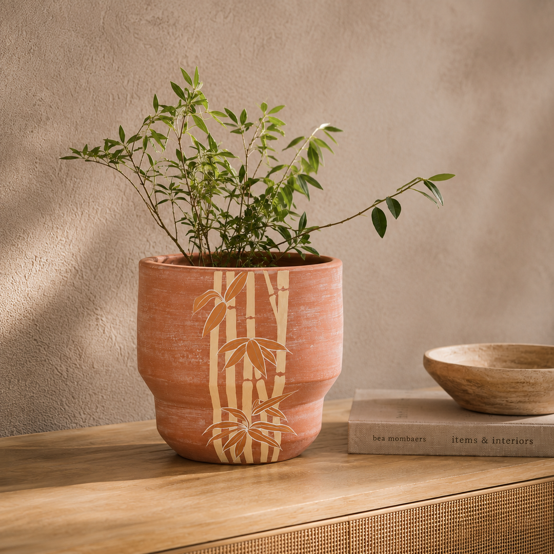 Japandi style terracotta plant pot sitting on an indoor wooden side table housing foliage 