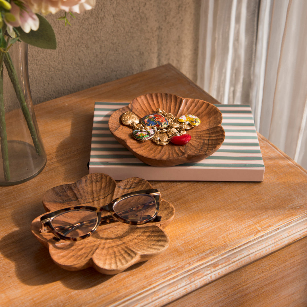 Set of four carved wood trinket dishes styled on a bedroom vanity holding rings and jewelry  