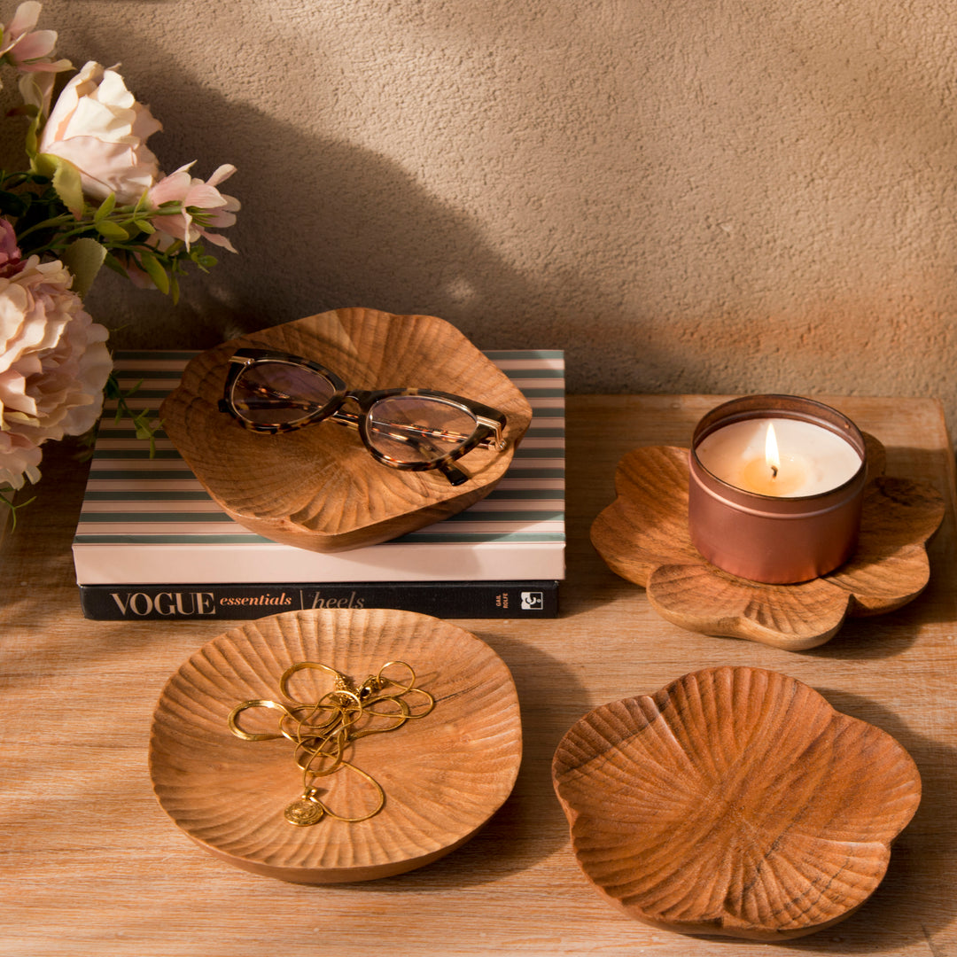 Set of four carved wood trinket dishes styled on a bedroom vanity holding rings and jewelry  