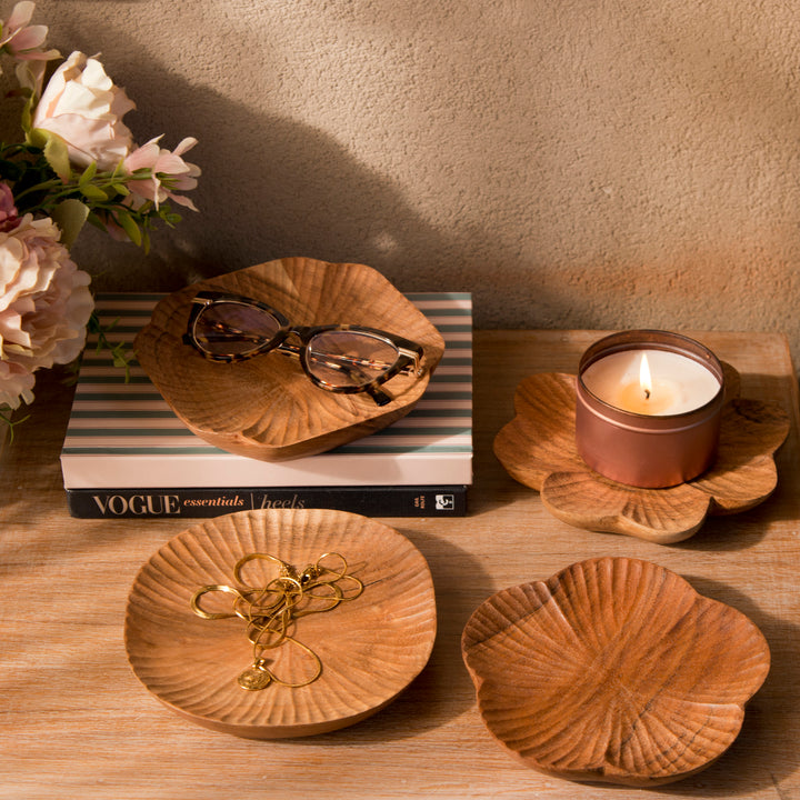 Set of four carved wood trinket dishes styled on a bedroom vanity holding rings and jewelry  