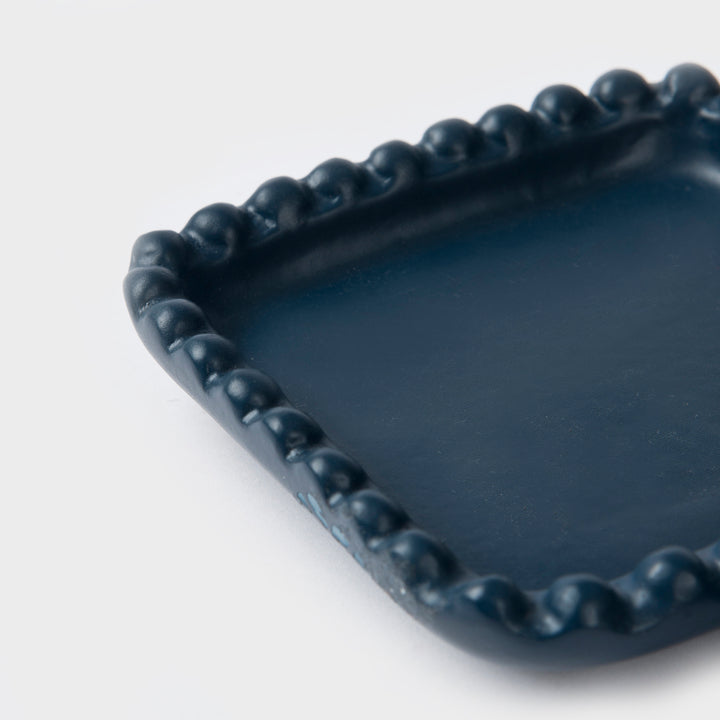 Close-up of the handcrafted terracotta trinket tray showcasing its matte indigo glaze and raised beaded edge detailing.