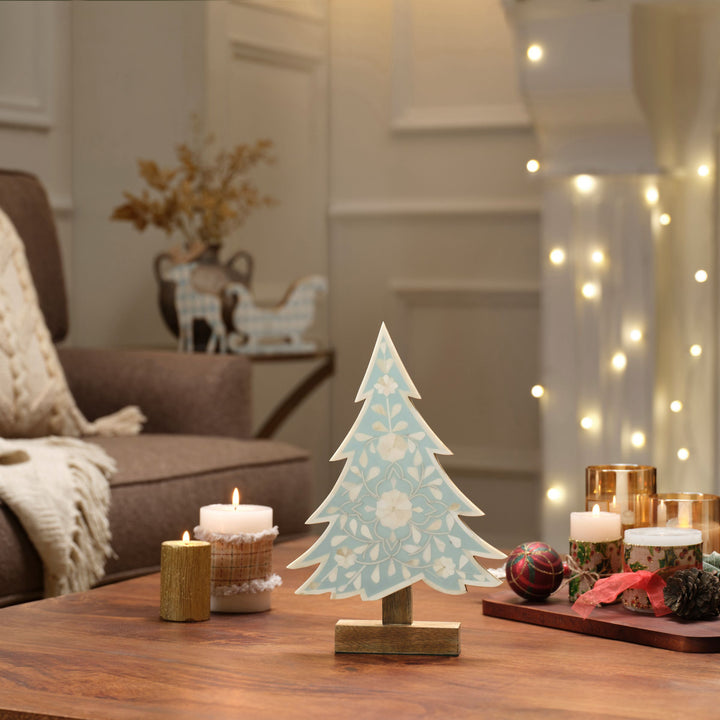 Teal blue and white floral bone inlay tree displayed on a holiday mantel with evergreen accents