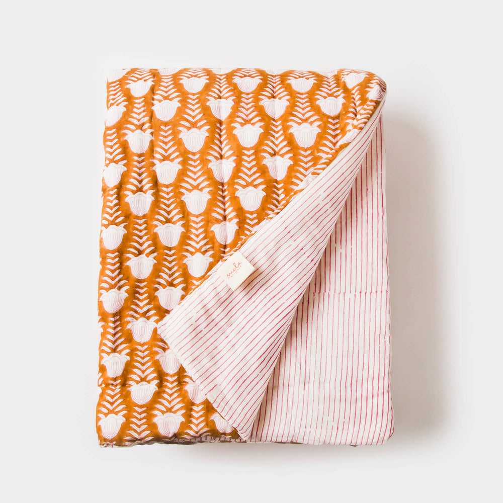 Orange handcrafted cotton throw displayed neatly folded